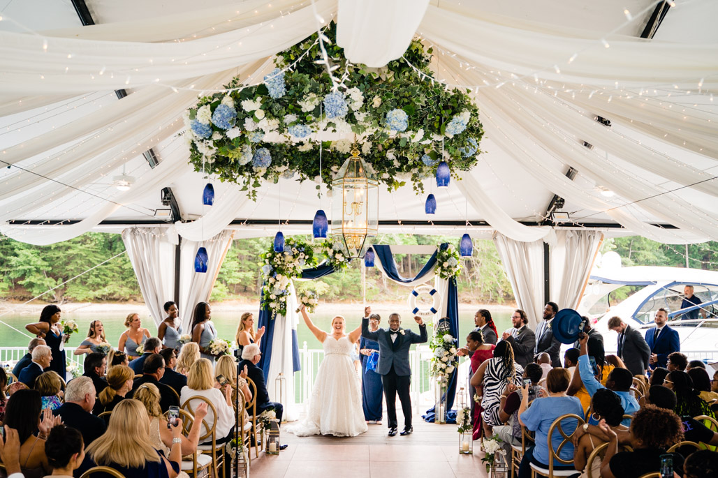 Bride and groom celebrating at a lakeside tented reception